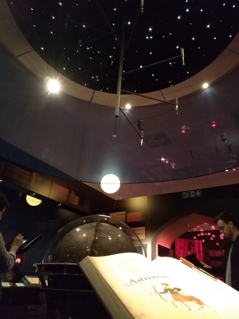 Section astronomie de l'expositon Harry de la British Library avec un globe et un système solaire au plafond